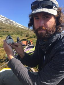 Devin in the field holding a Horned Lark, the subject of his PhD research